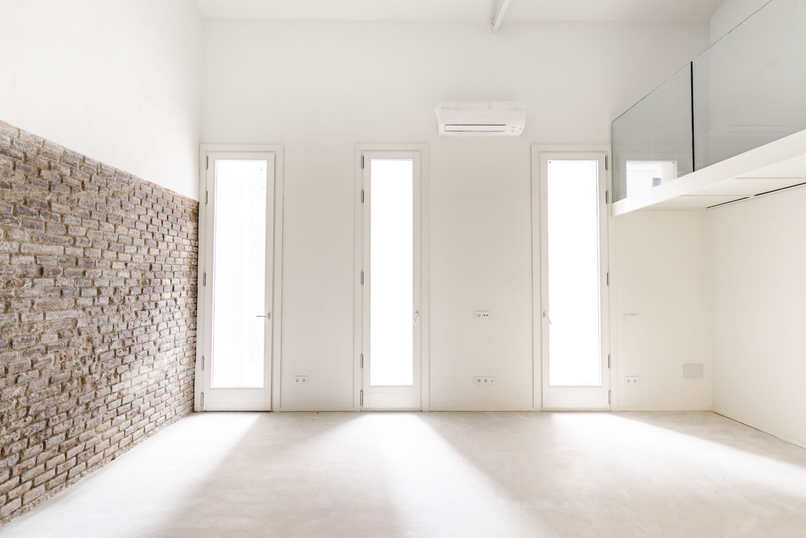 Interior rehabilitado con muro de ladrillo y huecos verticales en Aragó 479