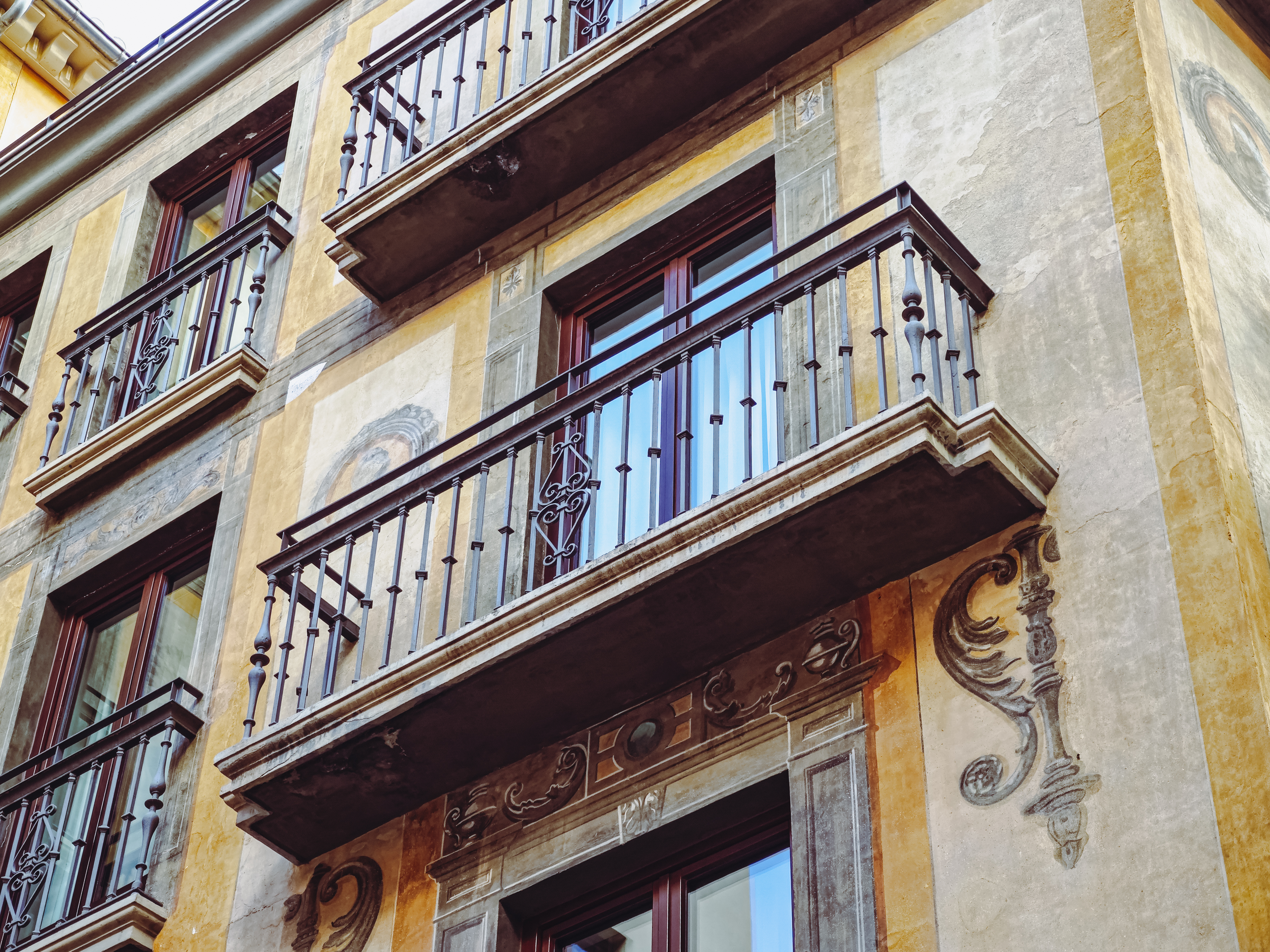 Detalle de una ventana de madera con balcón de forja en la fachada histórica del hotel