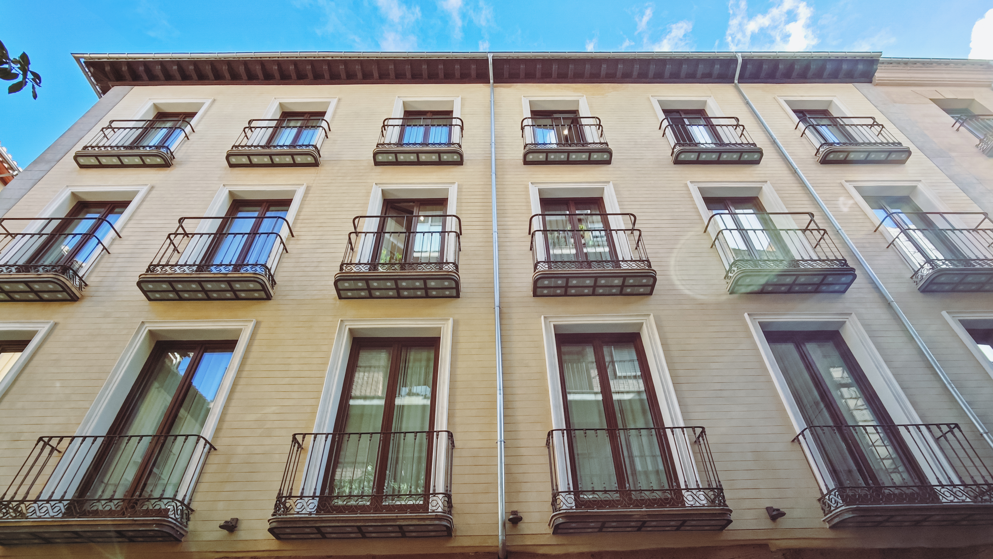 Fachada del hotel con balconeras de madera bajo el cielo de Granada