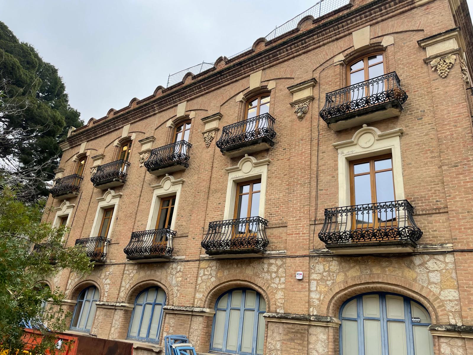 Vista de la fachada rehabilitada con ventanas y balcones de madera
